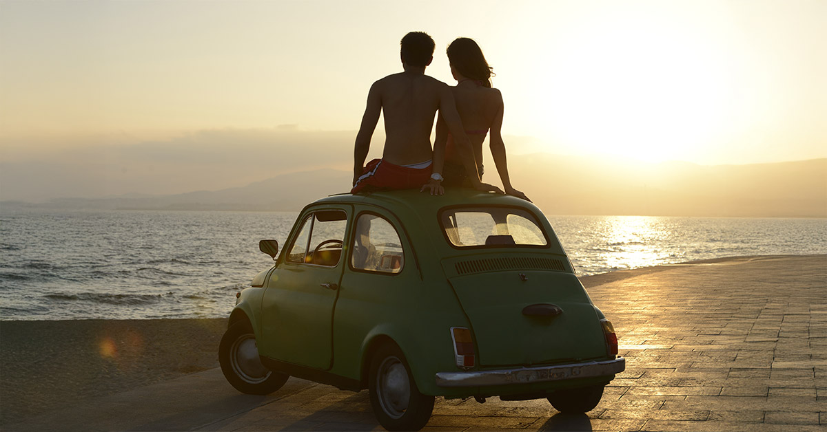 Romantic couple sitting on top of a car