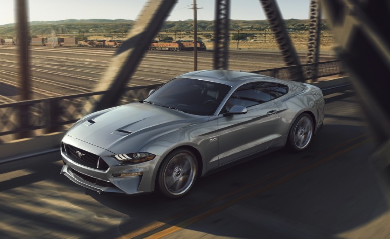 Ford Mustang driving over a bridge at sunset
