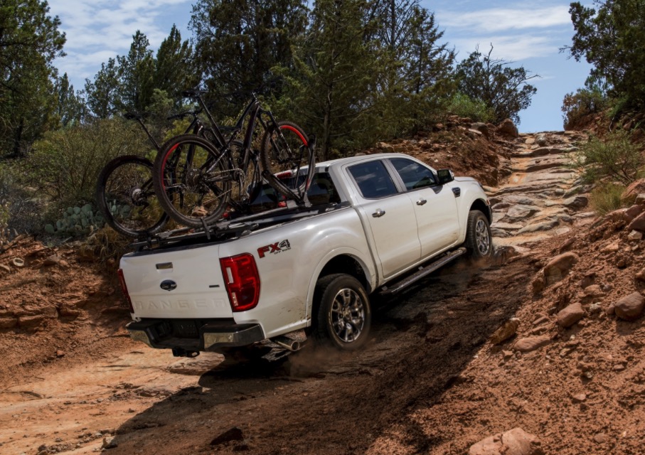 White Ford F-140 with bikes in the back driving off road