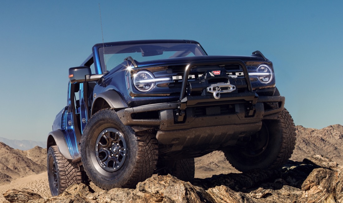 Blue Ford Bronco driving off road on a bright summer day