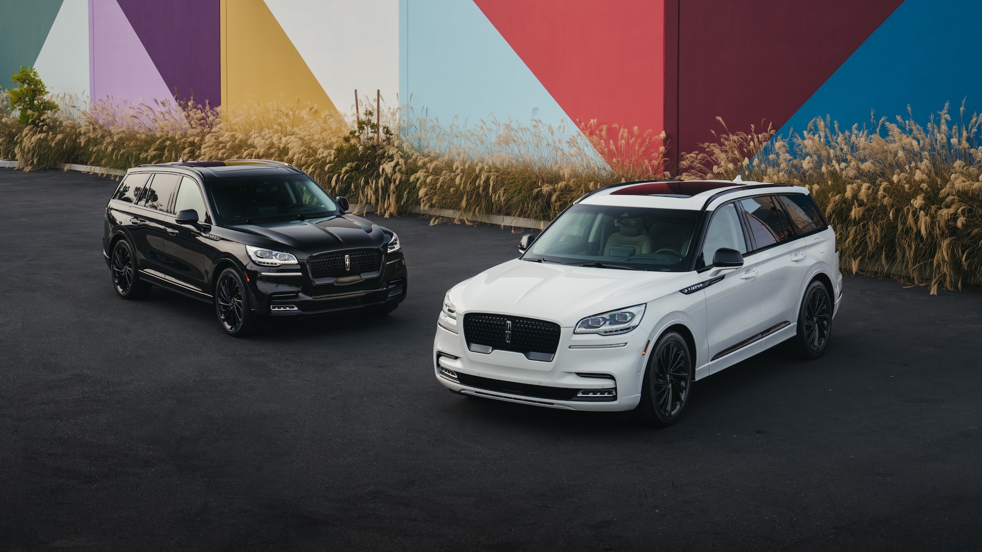 two Lincoln Navigators parked in front of a colorful building