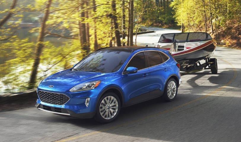 Blue Ford Escape pulling a boat on a trailer to a lake